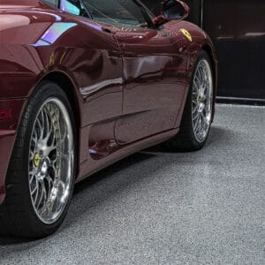 Red sports car parked on a gray full flake mica epoxy and polyaspartic garage floor. 