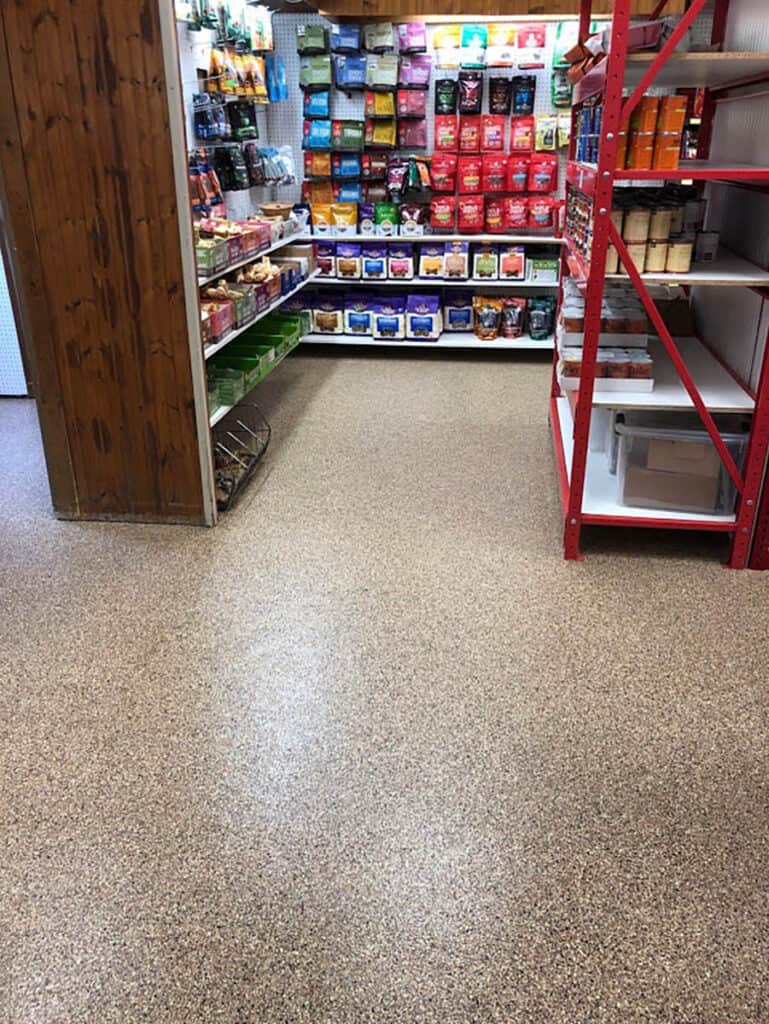 Shelving stocked with food items sits atop a beautiful full flake epoxy floor.