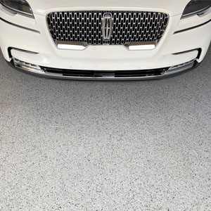 Gray full flake epoxy and polyaspartic flooring with a white Lincoln parked atop. 